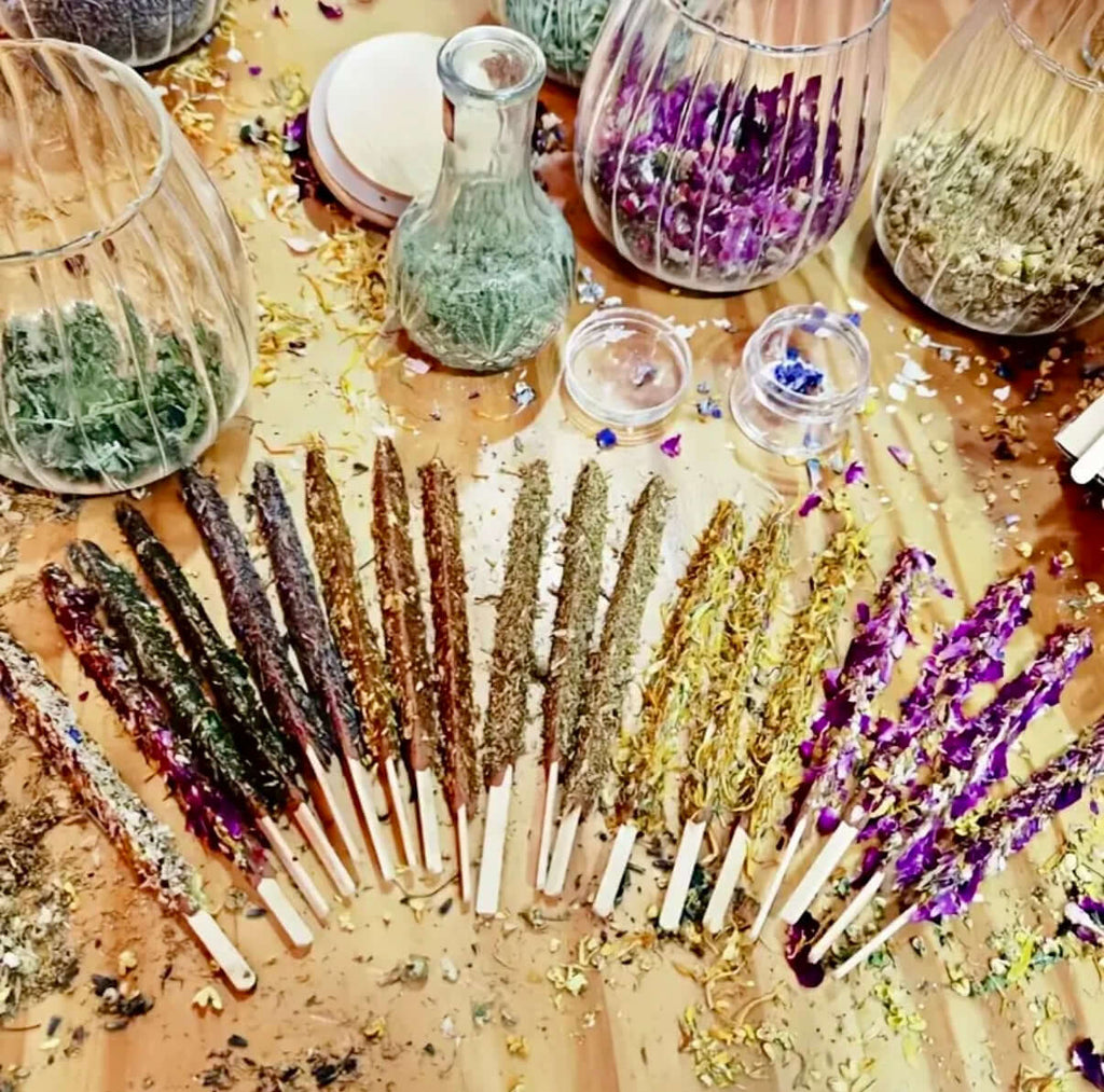 Artisan Dipped Palo Santo Ritual Sticks arranged on a wooden table with jars of herbs and flowers in the background.