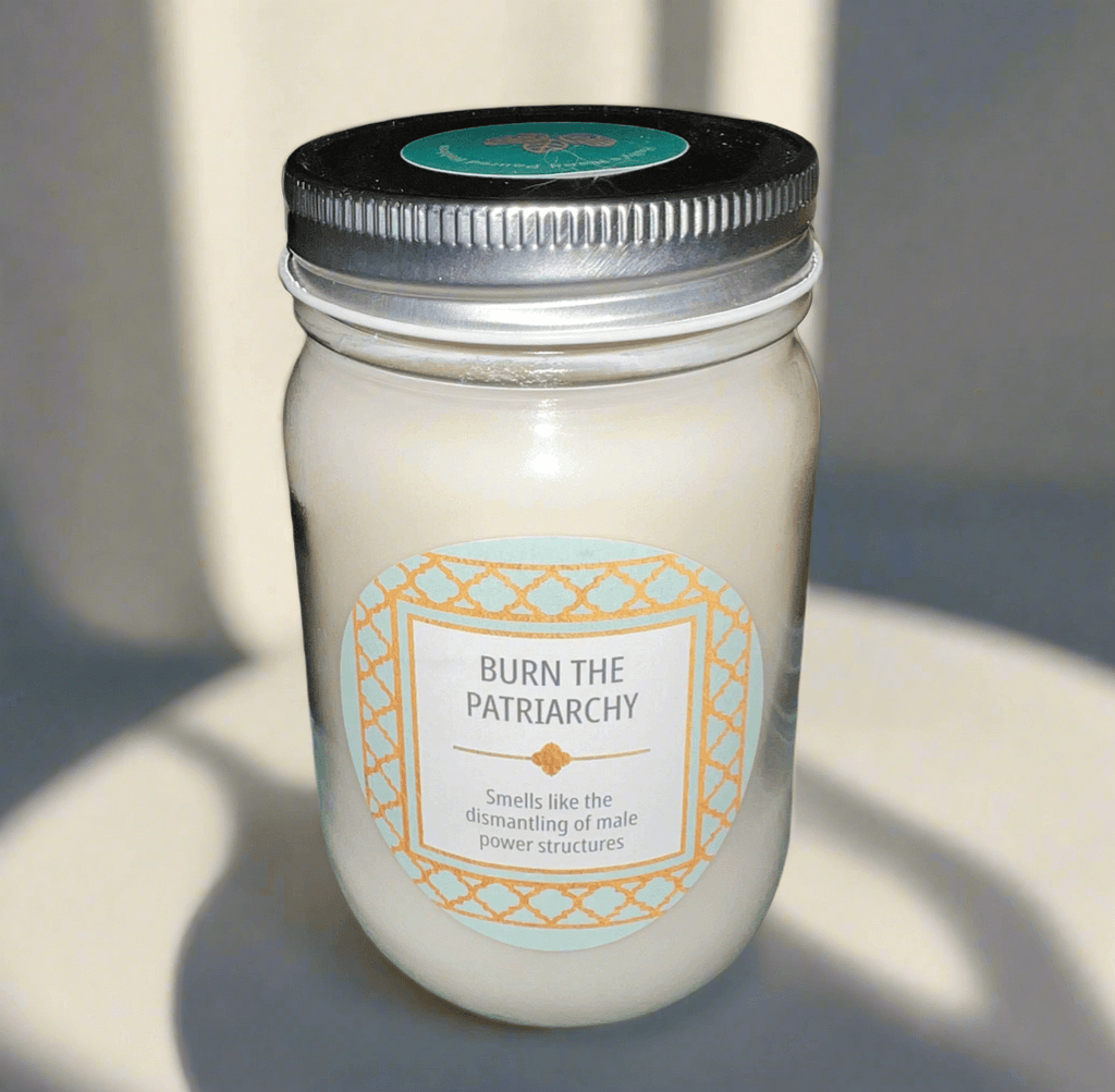 14 oz Burn the Patriarchy scented soy candle in glass jar with gold and turquoise decal, promoting feminist themes.